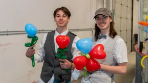 Deux jeunes hommes souriant avec des ballons en forme de coeur